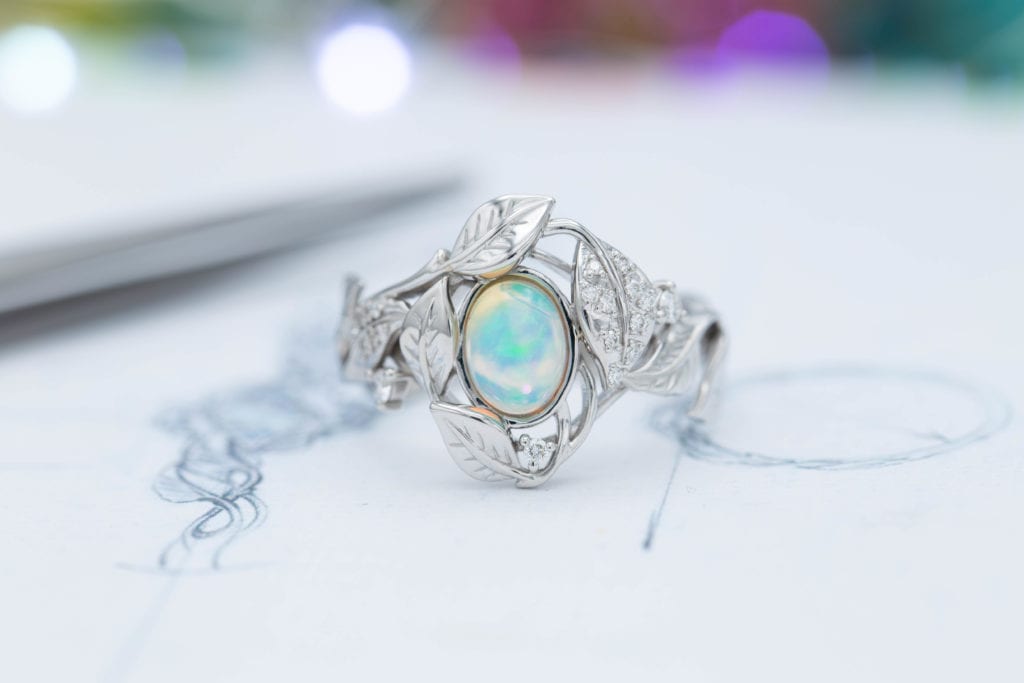 8 x 6 mm Opala branca etíope com muito fogo e cores cintilantes, incrustada em um design aberto e tortuoso de folha e videira com detalhes em diamante. Foto © CustomMade . Usado com permissão.